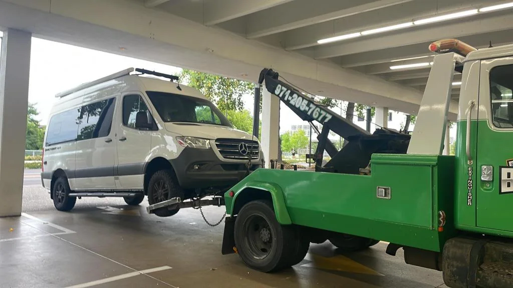 Commercial van being loaded for transport by a tow truck.
