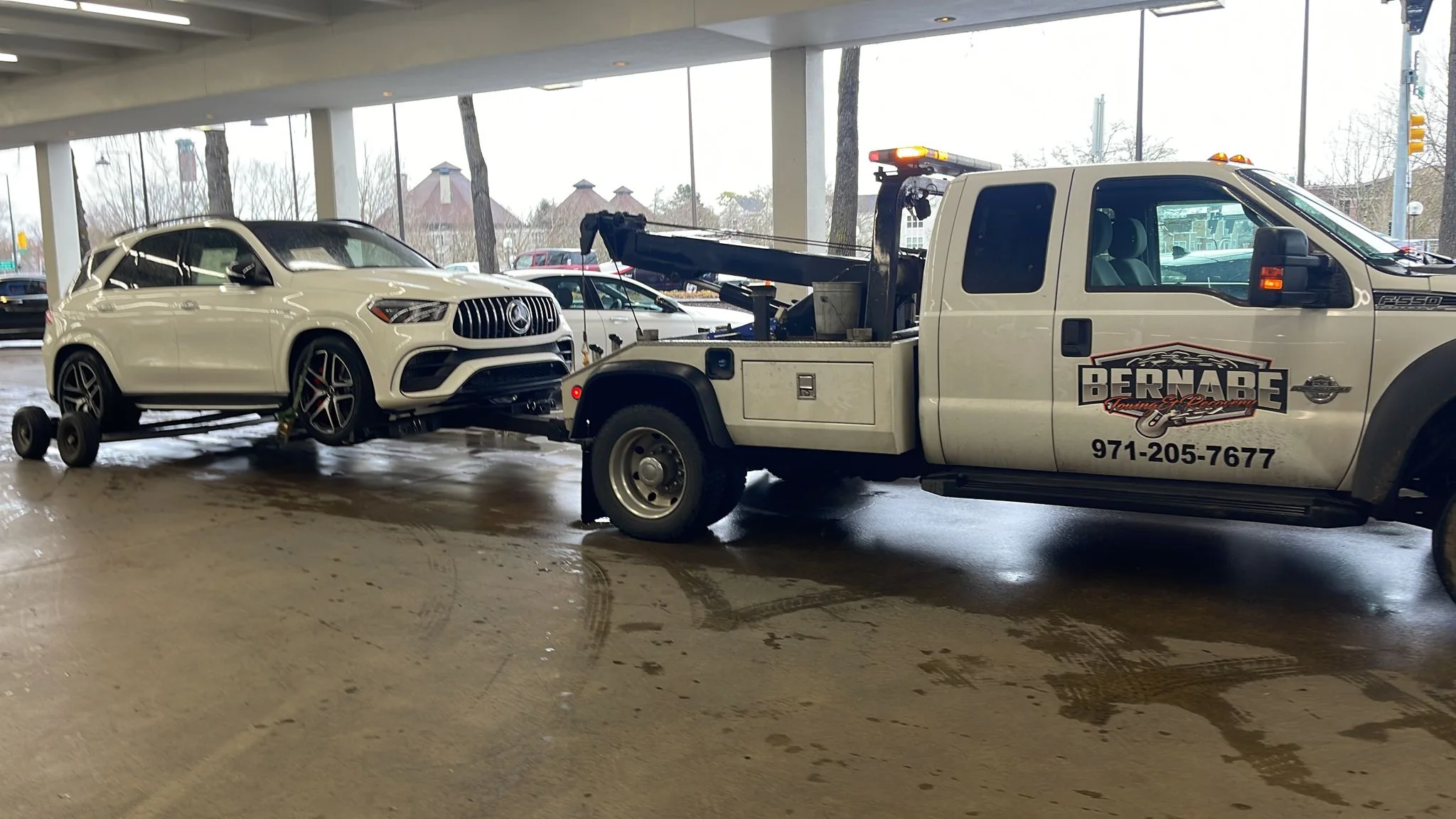 Bernabe Towing truck assisting with a vehicle in a parking garage.