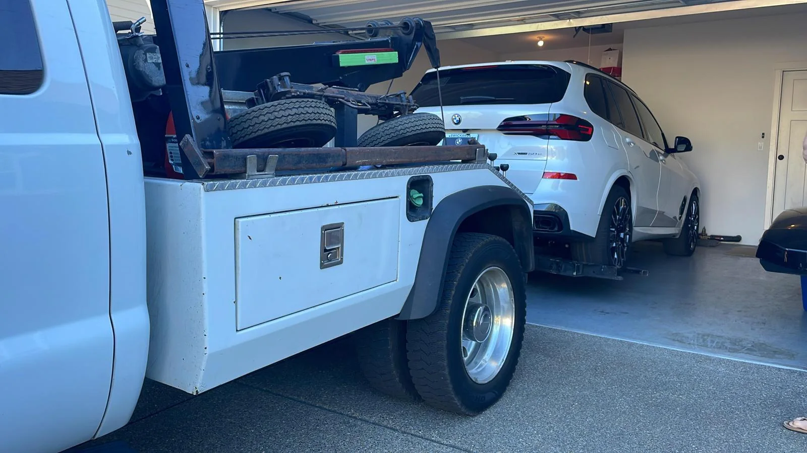 Wheel-lift tow truck assisting an SUV inside a parking garage.